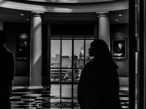 A view from inside the Michigan Supreme Court building frames the capitol building out the window while the shadow of Kyra in her robes walks in the foreground